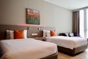 pokój hotelowy z 2 łóżkami i obrazem na ścianie w obiekcie Qliq Damansara Hotel w mieście Petaling Jaya