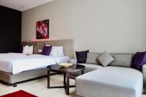 a hotel room with two beds and a couch at Qliq Damansara Hotel in Petaling Jaya
