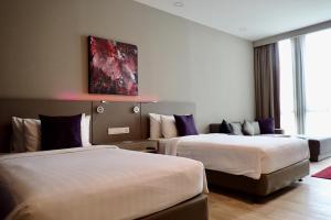 ein Hotelzimmer mit 2 Betten und einem Gemälde an der Wand in der Unterkunft Qliq Damansara Hotel in Petaling Jaya