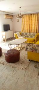 a living room with a table and yellow furniture at L'écurie orangerie in Hammamet Nord
