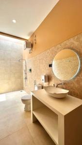 een badkamer met een wastafel, een toilet en een spiegel bij Sampai Villa Sahara in Yogyakarta