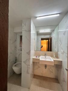 a bathroom with a sink and a toilet and a mirror at Royal Park Hotel Dockyard in Mumbai