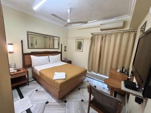 um quarto com uma cama, uma secretária e uma televisão em Royal Park Hotel Dockyard em Mumbai