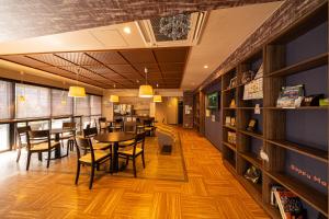 a dining room with tables and chairs and bookshelves at BEPPU HOSTEL U&T in Beppu