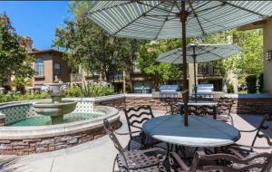a patio with tables and chairs with an umbrella at The Plaisir - Pool & Spa in Santa Clarita