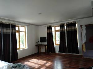 a bedroom with black and white curtains and a wooden floor at Hotel Leh Residency -Leh in Leh