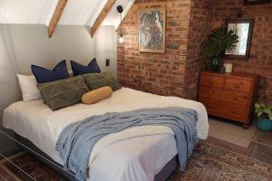a bedroom with a bed and a brick wall at Lacebark Cottage in Hilton