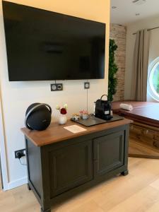 a room with a table with a television on a wall at Chambre romantique avec Jacuzzi privée in Messy