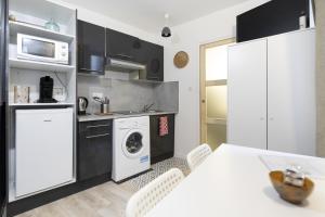 a kitchen with a washing machine and a table with chairs at Le petit MIAMI in Thionville