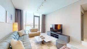 Primestay - District One Residences 16 - MBR في دبي: غرفة معيشة مع أريكة وتلفزيون