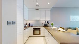 Primestay - District One Residences 16 - MBR في دبي: مطبخ مع دواليب بيضاء وغرفة معيشة