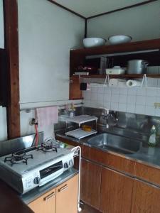 a kitchen with a stove and a sink at ゲストハウス　シン熊野 in Tanabe
