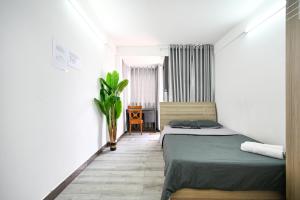 een slaapkamer met een bed en een plant erin bij Ohio Hotel & Apartment in Ho Chi Minh-stad