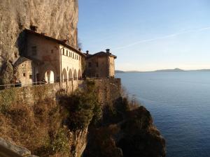 a building on the side of a cliff next to the water at Antico Borgo Del Lago Maggiore in Due Cossani