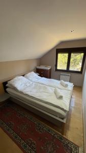 a bedroom with a bed with white sheets and a window at Vila Garden River Jahorina - Sarajevo in Mokro