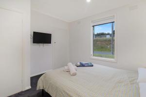a white bedroom with a bed and a window at Scenic Stay I Short or Long Term in Geelong