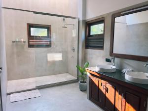 a bathroom with a shower and two sinks and a glass shower at Tsuru Villa in Udawalawe