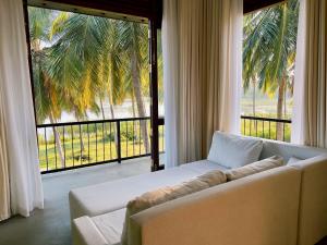 a living room with a couch and a large window at Tsuru Villa in Udawalawe