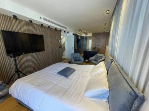 um quarto com uma grande cama branca e uma televisão em פנטהאוז 2 חדרים עם בריכה וג'קוזי em Haifa