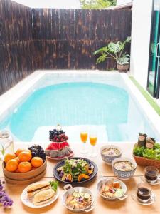 una mesa con comida y bebida junto a una piscina en Yada house onsen pool villa, en Ban Nong Saeng