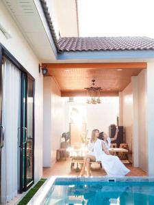 a bride and groom sitting on a bench next to a swimming pool at Yada house onsen pool villa in Ban Nong Saeng