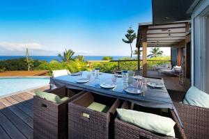 una mesa de comedor en un patio con vistas al océano en Maena - Magnifique Villa de 8 personnes avec piscine et vue mer proche du lagon de Saint-Leu en Saint-Leu