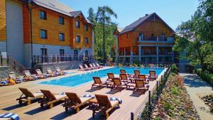 a swimming pool with lounge chairs and a hotel at Hotel Czarny Potok Resort SPA & Conference in Krynica Zdrój