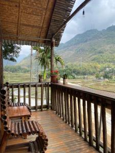 um alpendre de madeira com um banco e vista para uma montanha em Mai Chau La Vida Homestay em Mai Châu