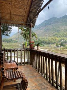 Un porche de madera con un banco y vistas a una montaña. en Mai Chau La Vida Homestay, en Mai Chau