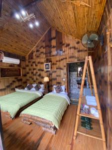 Mai Chau La Vida Homestay في ماي تشاو: سريرين في غرفة بجدران خشبية