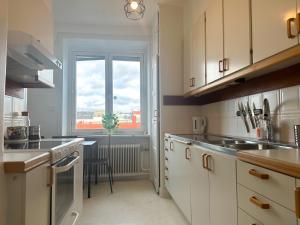 a kitchen with white cabinets and a large window at Stay Inn Apartment Sveavägen in Stockholm