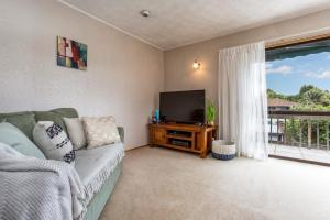 uma sala de estar com um sofá e uma televisão de ecrã plano em Prime Location! 4BR Sunny Character Home near CBD Auckland em Auckland