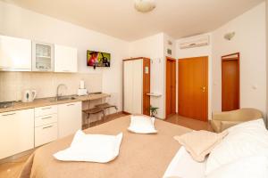 Apartmani Trogir في تروغير: مطبخ مع دواليب بيضاء وسرير في الغرفة