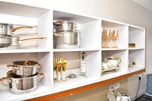 une cuisine avec des étagères blanches, des casseroles et des poêles dans l'établissement Meshivon suite, à Nairobi