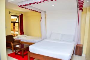 NarokにあるOlive Hotel Narokのベッド2台、テーブル、椅子が備わる客室です。