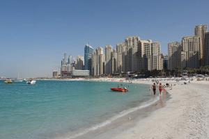 a beach with a group of people in the water at Dubai Marina Next to Metro and JBR Beach - CityApartmentStay in Dubai