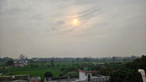 a view of a field with the sun in the sky at LDS Homestay in Rāmnagar