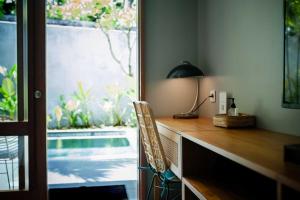 a desk with a lamp and a chair next to a pool at Ecozy Dijiwa Canggu in Canggu