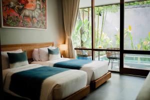 two beds in a room with a large window at Ecozy Dijiwa Canggu in Canggu