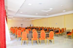 une salle de conférence avec des chaises et des tables orange dans l'établissement Olive Hotel Narok, à Narok