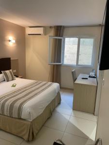 een hotelkamer met een bed, een bureau en een raam bij Hôtel A Madonetta in Bonifacio