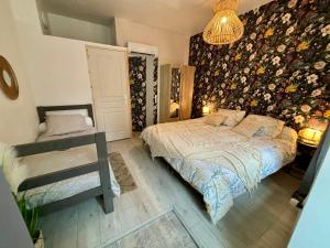 1 dormitorio con cama y pared de flores en Le studio «des Terroux », 