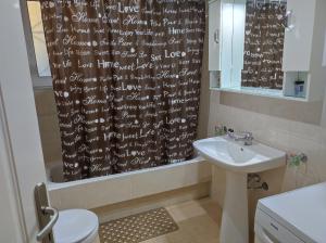 a bathroom with a shower curtain with writing on it at Galini Apartments in Kalamata