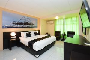 Schlafzimmer mit einem Bett, einem Schreibtisch und einem TV in der Unterkunft OYO 2487 Sampurna Jaya Hotel in Tanjung Pinang 
