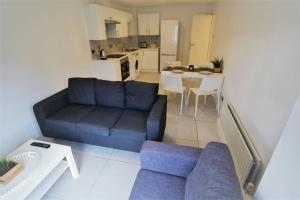 ein Wohnzimmer mit einem blauen Sofa und einer Küche in der Unterkunft 3 Bed - Close to City Centre, LGI and Uni of Leeds - Long Stay Rates in Headingley