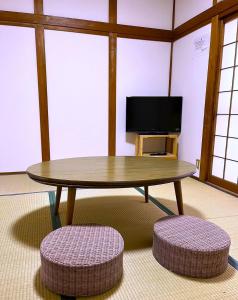 una mesa y dos taburetes en una habitación con TV en Guesthouse法華寺Yoshikawa, en Nara