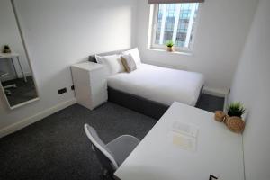 a small room with a bed and a desk and a table at 3 Bed - Close to City Centre, LGI and Uni of Leeds - Long Stay Rates in Headingley