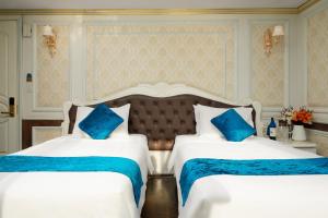 two beds in a hotel room with blue pillows at La Renta Premium Cruise in Ha Long