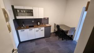 una pequeña cocina con armarios blancos y una mesa en Apartment- Zimmer Pernter, en Köflach