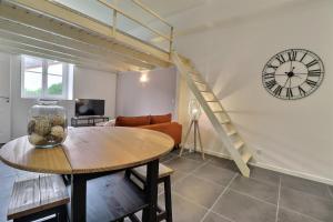 Una sala de estar con una mesa y un reloj. en La Malterie Loft in old factory - Mon Groom, en La Chapelle-Saint-Luc